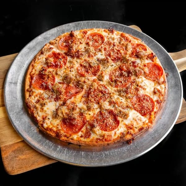 A freshly baked pepperoni and sausage pizza on a metal pan, resting on a wooden board.